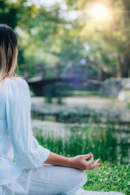 Su kenarında meditasyon. Suda meditasyon yapan genç bir kadın, yoga yaptıktan sonra dinlenme, yeşil doğa geçmişi..