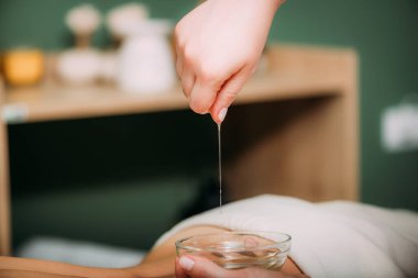 Masaj yağı. Kadınların sırtına aromatik masaj yağı döken terapist. 