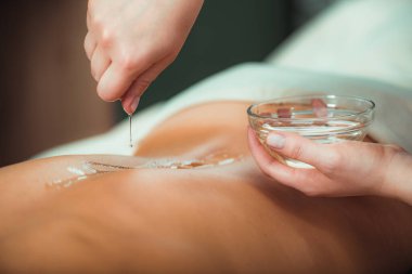 Masaj yağı. Kadınların sırtına aromatik masaj yağı döken terapist. 