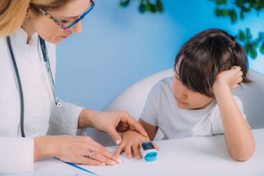 Pulmonoloji çocuk doktoru, nabız oksimetresiyle kan oksijeni seviyesini ölçüyor. 