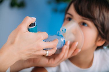Pulmonolog Küçük Çocuğa Aero odasında yardım ediyor. Pediatrik pulmonolog, solunum sistemi, akciğerler, bronşiyal tüpler, nefes borusu ve nefes borusu hastalıklarının teşhisi ve tedavisi konusunda uzman tıp doktoru.