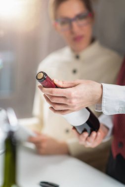 Sommelier eğitim kursu. Bir şarap garsonu şarap şişesindeki etiketten önemli bilgileri okuyarak öğrencilere üzüm çeşidini, mahsulü, bölgeyi ve diğer önemli detayları nasıl tanımlayacaklarını öğretir..