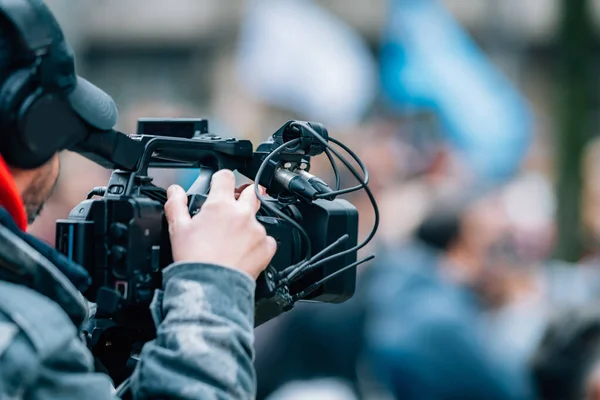 stock image Making news, media cameraman at a public protest, blurred crowd in the background