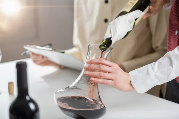 酒量下降 酒保把红酒从酒瓶中倒入酒瓶 同时解释如何给红酒充气以改善葡萄酒的味道和香味 — 图库照片