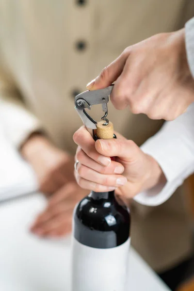 ワインサービスとホスピタリティトレーニング ソムリエが赤ワインのボトルからコルクを取り除き ゲストにワインを提供するための適切な技術を示しています — ストック写真