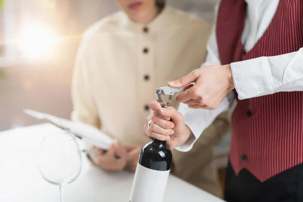 서비스와 적포도주 병에서 코르크를 꺼내어 손님들에게 포도주를 대접하는 기술을 보여준다 — 스톡 사진