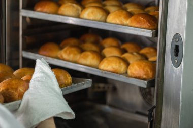 Fırında pişmiş çörekleri restoran mutfağından çıkartıyor. 