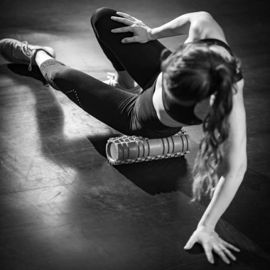 Woman Using Foam Roller to Self-Massage Muscles in the gym