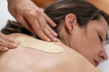 Bitkisel sırt ağrısı giderme bandı geleneksel Çin ilaçları bitkisel tedavi. Kadın eli hastaların sırtına yapışkan bitkisel alçı uyguluyor. 