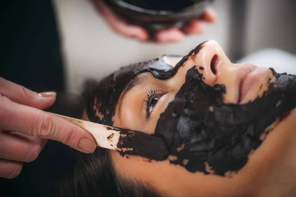 女性の顔にチョコレートマスクを塗る — ストック写真