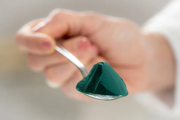 Spoon filled with nutrient-rich supefood spirulina, cyanobacteria or bluegreen algae, showcasing its vibrant color and health benefits