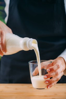 Kefir 'i bardağa dolduran kadın. Doğal probiyotik Lacto ve Bifido Bakterisi açısından zengin sağlıklı mayalanmış bir süper yiyecek içeceği.