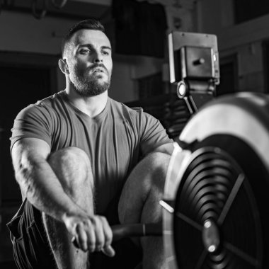 Çapraz eğitim sırasında kürek çekme egzersizi yapan genç adam, dinamik siyah beyaz fotoğraf 