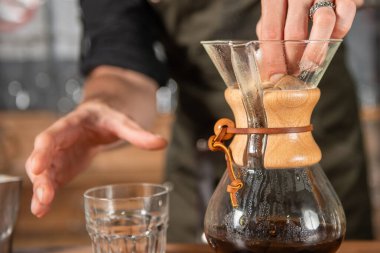 Yetenekli barista titizlikle bir Chemex kahvesi hazırlıyor, bu da bardakları doldurma sanatını gösteriyor.
