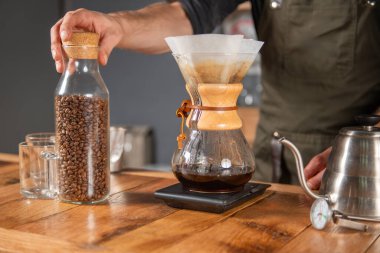 Yetenekli barista titizlikle bir Chemex kahvesi hazırlıyor, bu da bardakları doldurma sanatını gösteriyor.