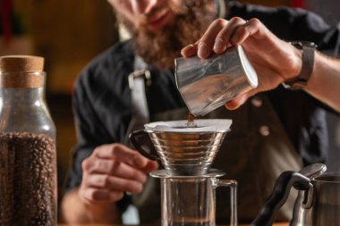 Skilled barista using the Kalita Wave dripper coffee maker to create a meticulously brewed cup of coffee clipart