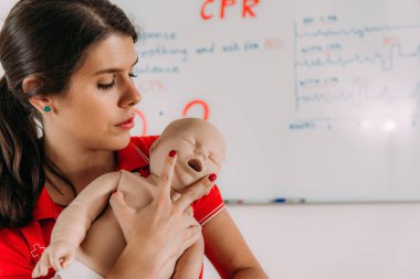 İlk yardım eğitiminde bebek suni teneffüs yapmayı öğrenmek - bebek mankeni kullanarak kardiyopulmoner canlandırma dersi.