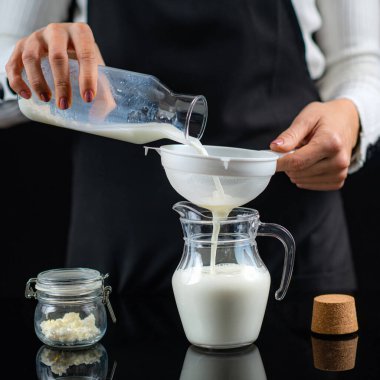 Sütü kefir tanecikleriyle lekelemek. Kadın evde kefir yapıyor..