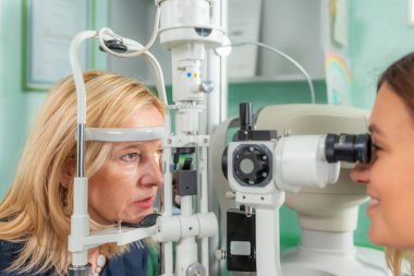 Göz doktoru olarak yarık lamba kullanan bir hastayı muayene eder.