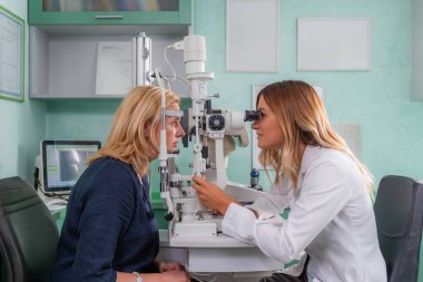 Profesyonel göz doktoru ayarında kesik lambayla göz muayenesi.