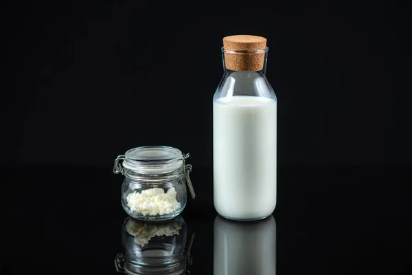 自家製ケフィア 黒い背景に瓶とミルクの瓶にケフィアの穀物 — ストック写真