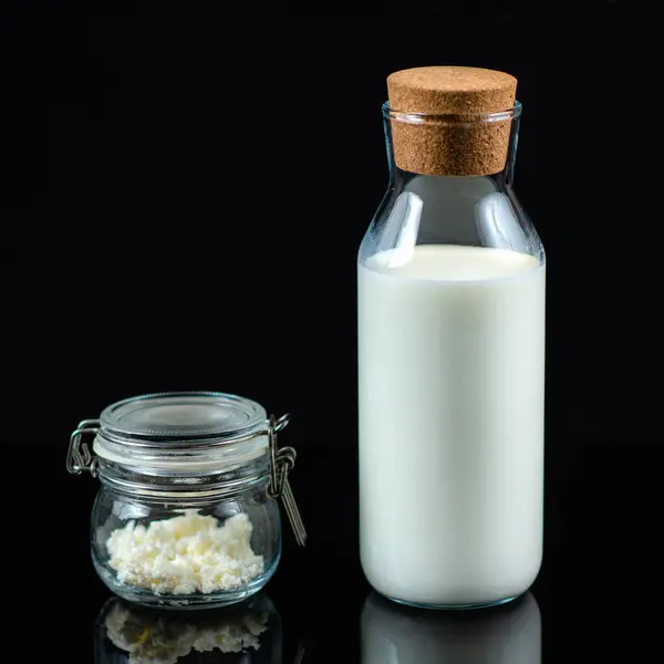 自家製ケフィア 黒い背景に瓶とミルクの瓶にケフィアの穀物 — ストック写真