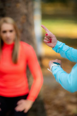 Kadınlar sonbaharda halka açık parkta egzersiz yapıyor. Eğitmen Bekleme Yapan Kadına Bakıyor.
