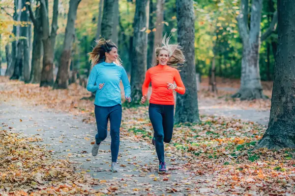 Two Women Jogging Outdoors in Public Park in the Fall.