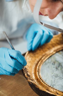 Antik bir altın çerçeveyi restore eden kadın