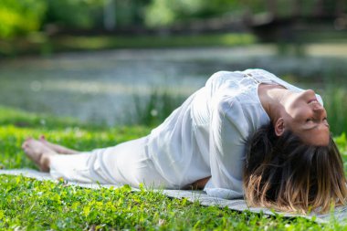 Kadın zarifçe yoga yapıyor, doğası gereği barış ve sükunetle dolu.