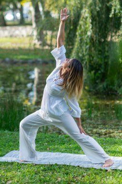 Kadın yoga yapıyor, doğa ve iç huzuruyla bağlantı kuruyor.