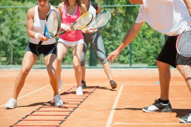 Yüksek enerjili bir kardiyo tenis antrenmanına katılan enerjik grup, fitness ve tenis becerilerini birleştirdi