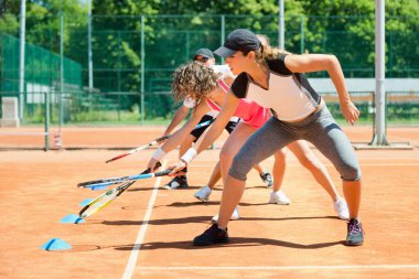 Yüksek enerjili bir kardiyo tenis antrenmanına katılan enerjik grup, fitness ve tenis becerilerini birleştirdi