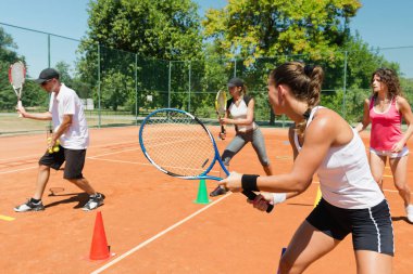 Yüksek enerjili bir kardiyo tenis antrenmanına katılan enerjik grup, fitness ve tenis becerilerini birleştirdi