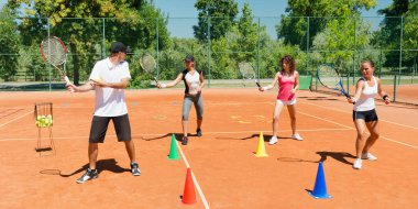 Yüksek enerjili bir kardiyo tenis antrenmanına katılan enerjik grup, fitness ve tenis becerilerini birleştirdi