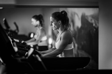 Koşu bandında egzersiz yapan kadın sporcu, siyah ve beyaz.