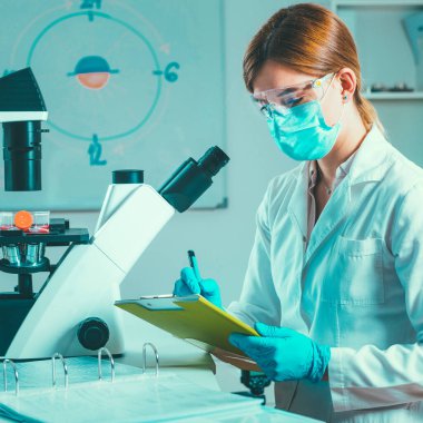 Bilimsel laboratuvar araştırması. Biyoteknoloji bilimcisi not alıyor.