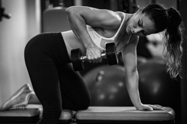 Triseps egzersizi yapan bir kadın spor salonunda, siyah ve beyaz.