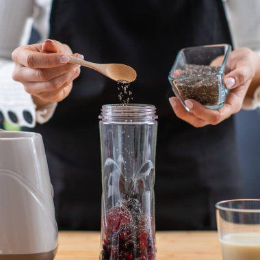 Kadın sağlıklı ve lezzetli bir ikram için besin karışımı böğürtlen ve bitki proteini hazırlıyor..