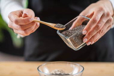 Yulaf ezmesi ve chia tohumlarının güzelliğini birleştiren süper yiyeceklerle kahvaltı hazırlayan bir kadın..
