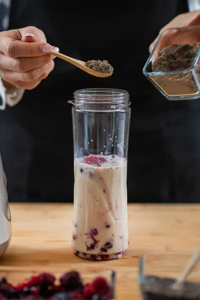 woman putting berries and plant protein powder in blender, creating a deliciously nutritious shake