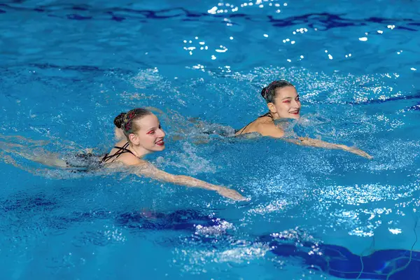 在闪烁的池水中 双人游泳表演时的精准与优雅 — 图库照片