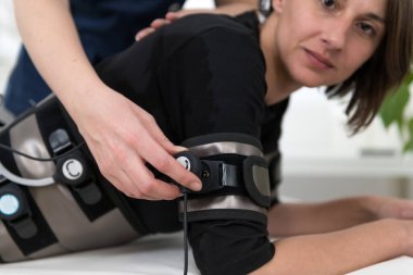 Vücudu elektro uyarı EMS terapisi ile donatıyorum. Salon terapisti kadın müşteriler için vücut hatlarını geliştirmek ve şekillendirmek için elektrotlar kullanır..