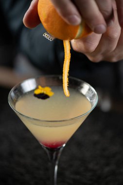 Barmen nazikçe taze portakal yığıyor, Ginger Apple Vermut Kokteyline narenciye ilave ediyor..