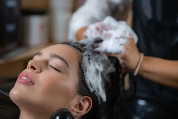 stock image Hairdresser applies shampoo to woman's hair in a salon, offering professional hair care expertise
