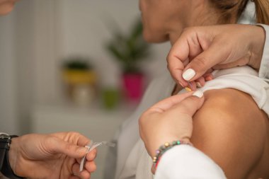 Akapunkturcu, ağrıyı azaltmak için kadının omzuna iğne batırıyor.