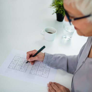 Sudoku bulmacaları, kıdemli bir kadın bilişsel terapi, zihinsel keskinlik ve problem çözme becerilerinden faydalanır.