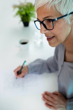 Kıdemli bir kadın, zihinsel keskinlik ve bilişsel becerileri geliştirmek için bilişsel terapinin bir parçası olan Sudoku bulmacalarını çözmekten hoşlanır.