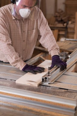 Marangozluk atölyesinde daire testeresi kullanan el işçisi