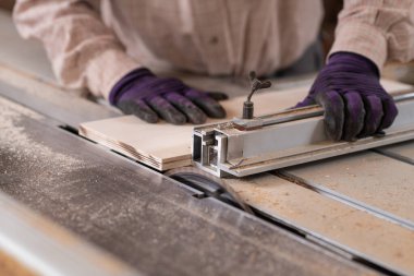 Marangozluk atölyesindeki dairesel testere makinesini kullanarak marangoz elinin resmini kapat